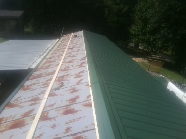 Old rusted panels beside newly installed green metal roofing — Wind Damage Roof Repair by Roofing Brothers in Eureka
