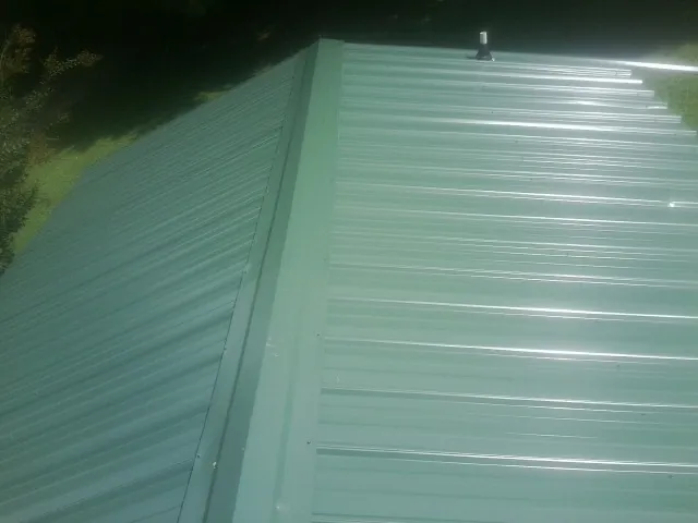 New green metal panels meeting at the ridge of a roof — Flat Roof Repair work by our crew in Eureka