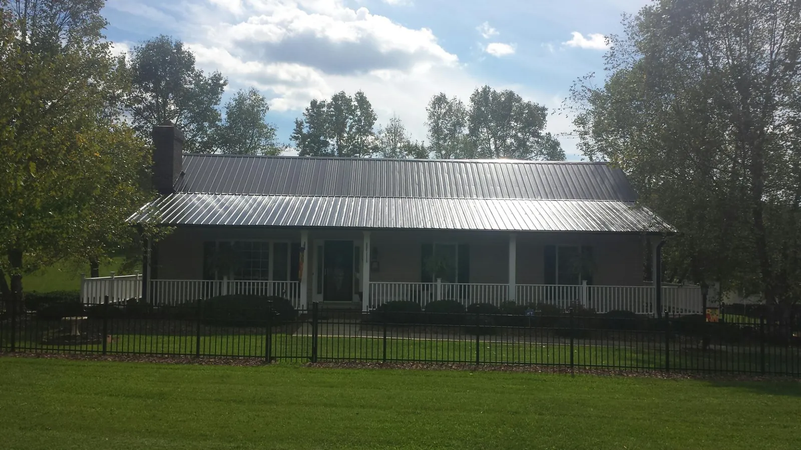 Gray metal roof on a brick ranch with a full width front porch — Gutter Guard Installation work by our crew in Eureka